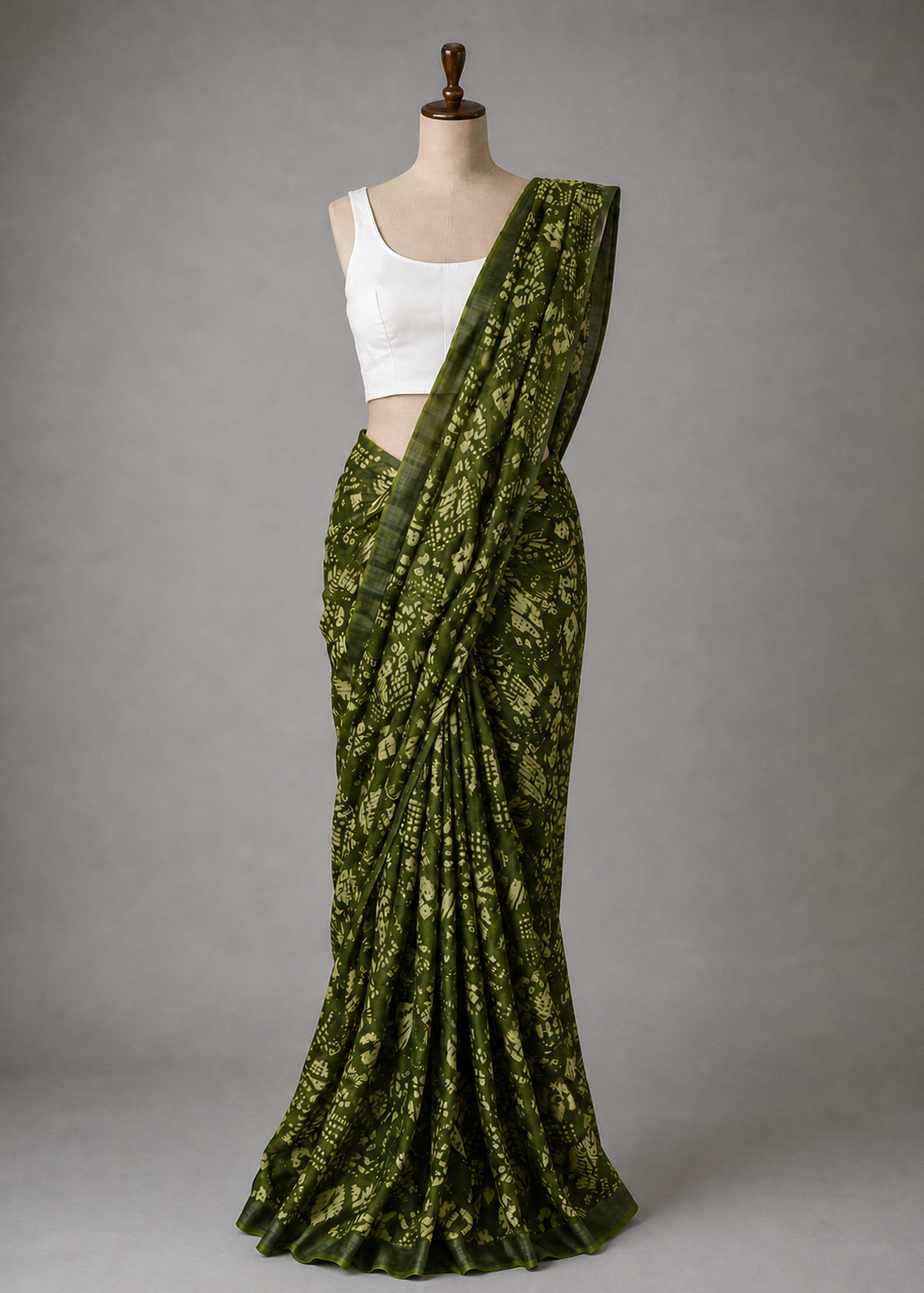 Green saree with a white blouse on a mannequin against a gray background