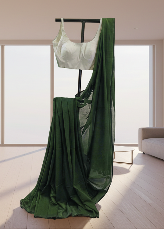 Green mul cotton saree draped over a mannequin with a white top in a minimalistic room.