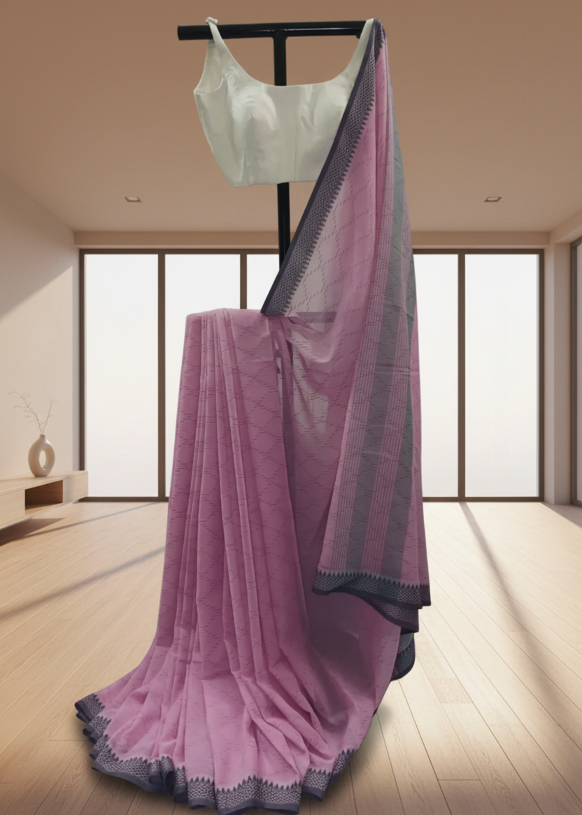 Pink cotton saree with black border draped over a black rod in a room with large windows.