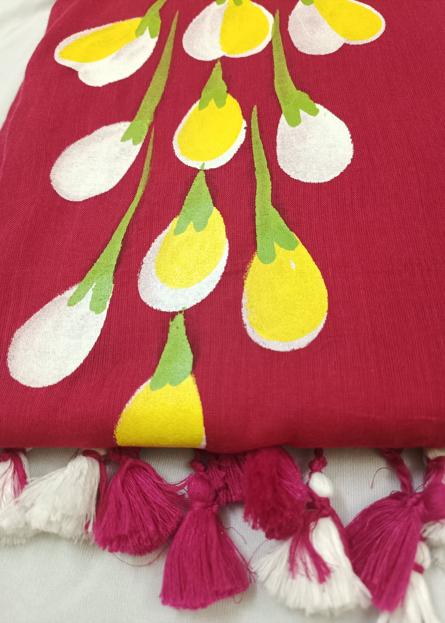 Red fabric with yellow and white floral patterns and pink tassels on a white background