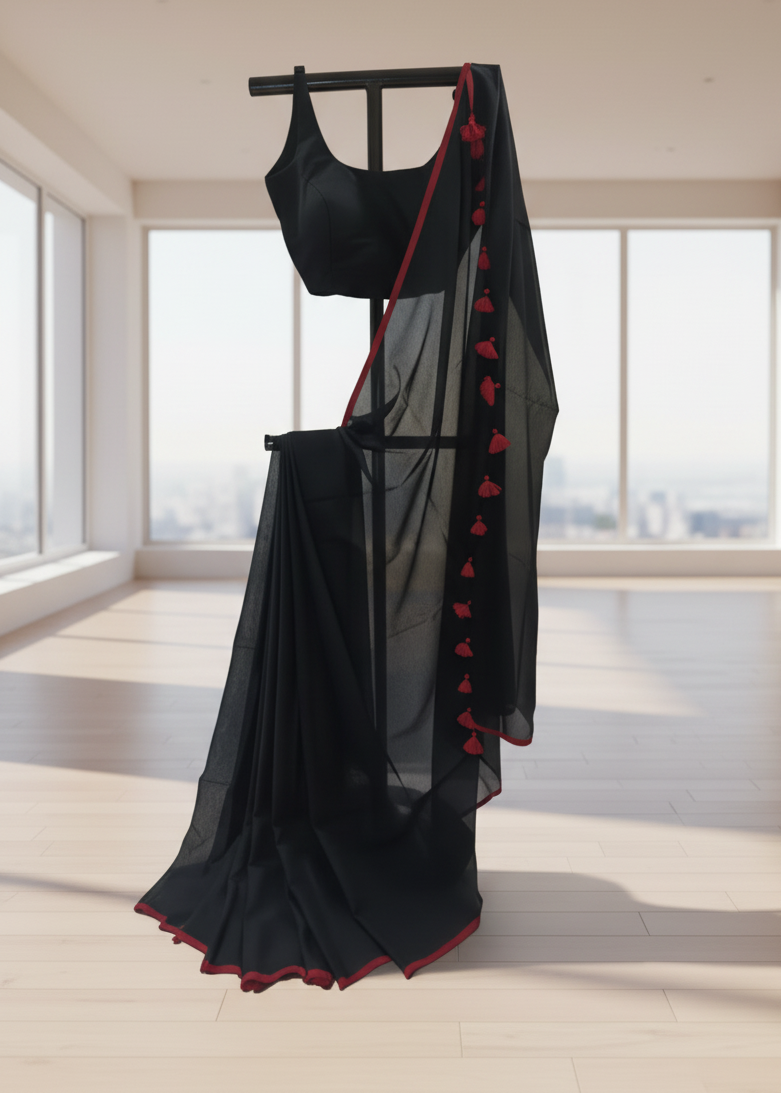 Black saree with red border on a stand in a bright room with large windows.