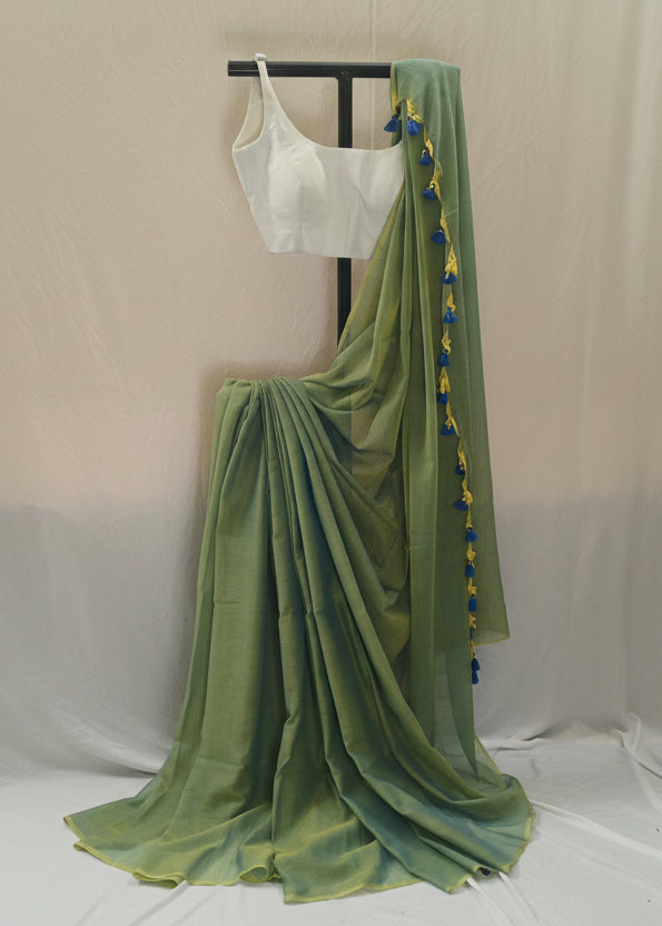 Green saree with a white blouse on a stand against a plain background
