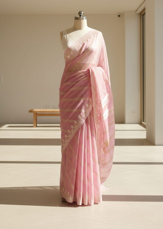 Pink saree with a gold border on a mannequin against a neutral background