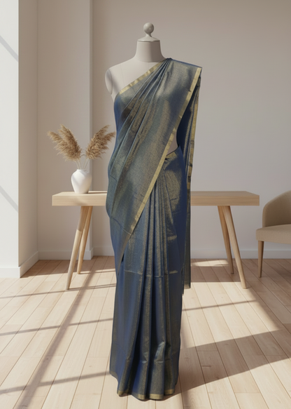 Blue linen saree draped over a mannequin in a room with wooden floor and white walls