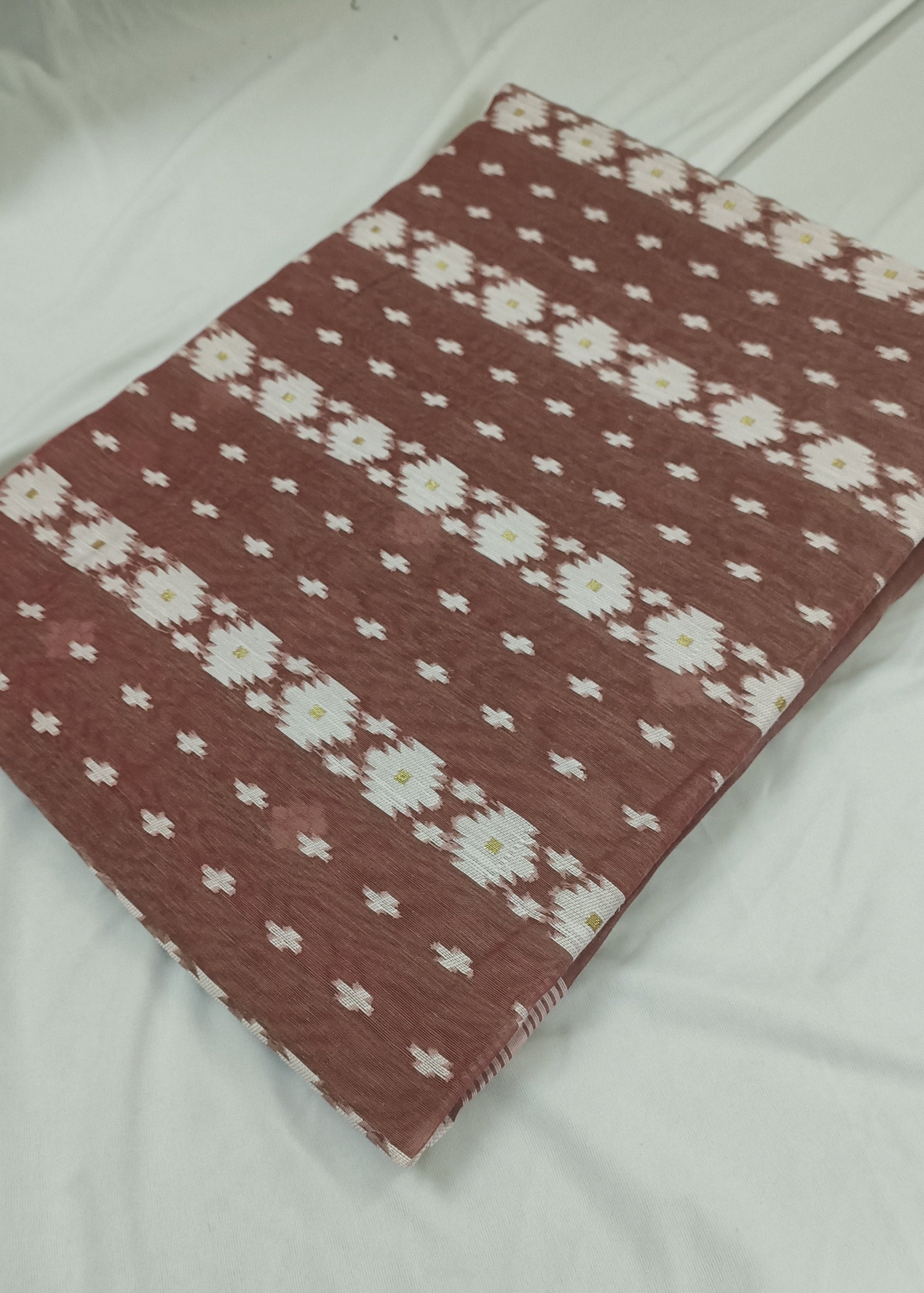 Red and white patterned blanket on a white bed