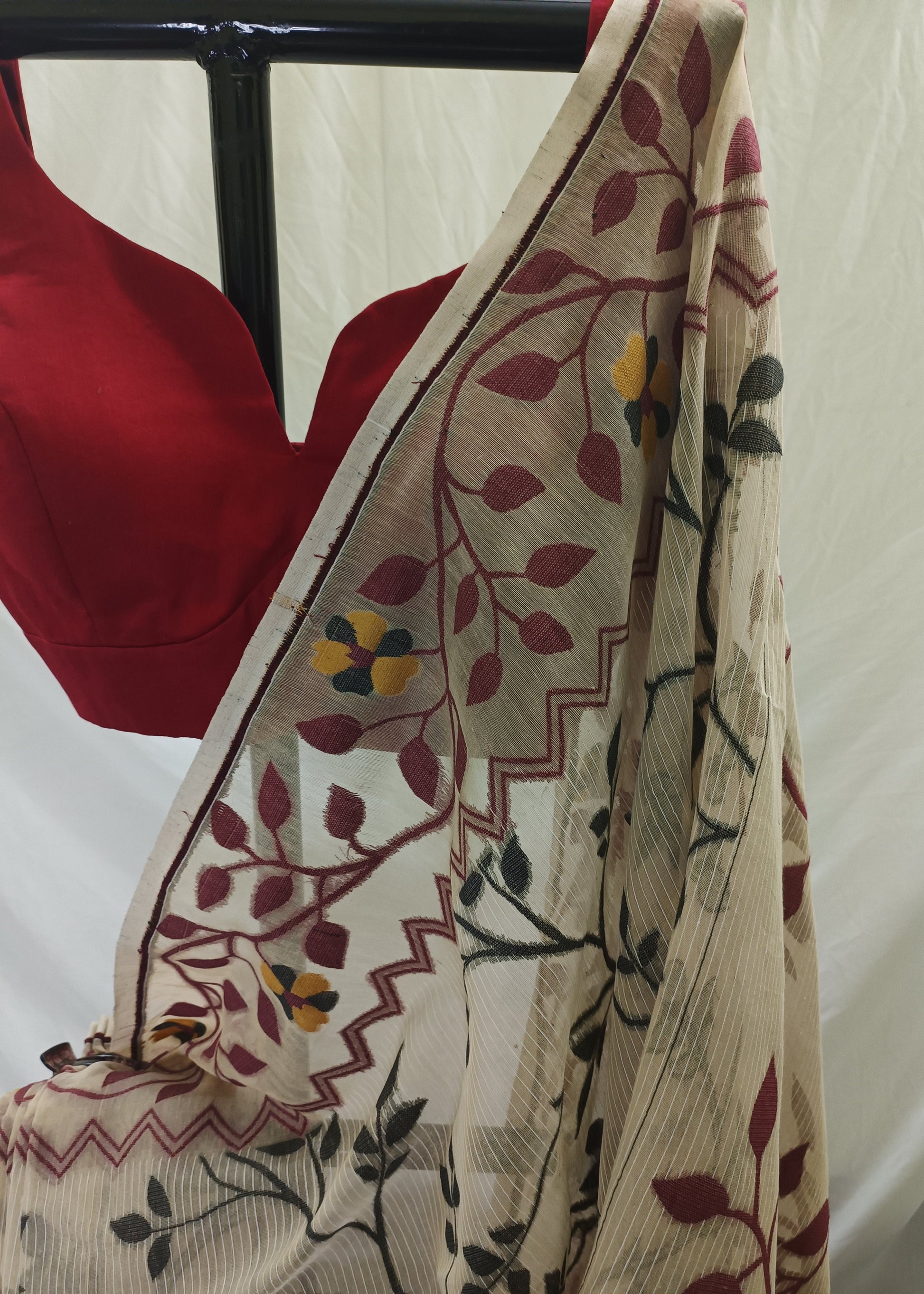Beige scarf with floral patterns draped over a red garment on a white background