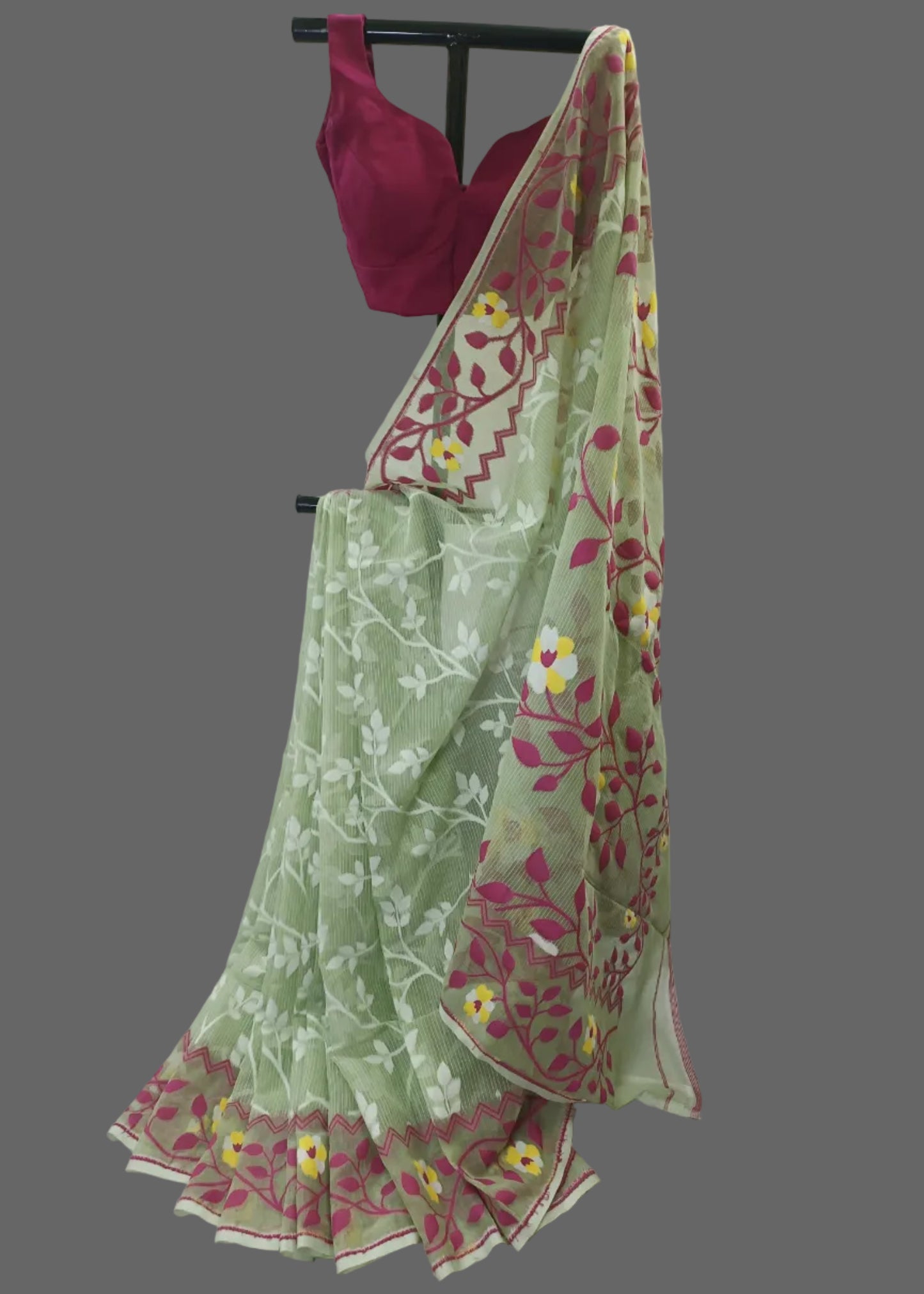 Green saree with floral patterns draped over a pink blouse on a white background