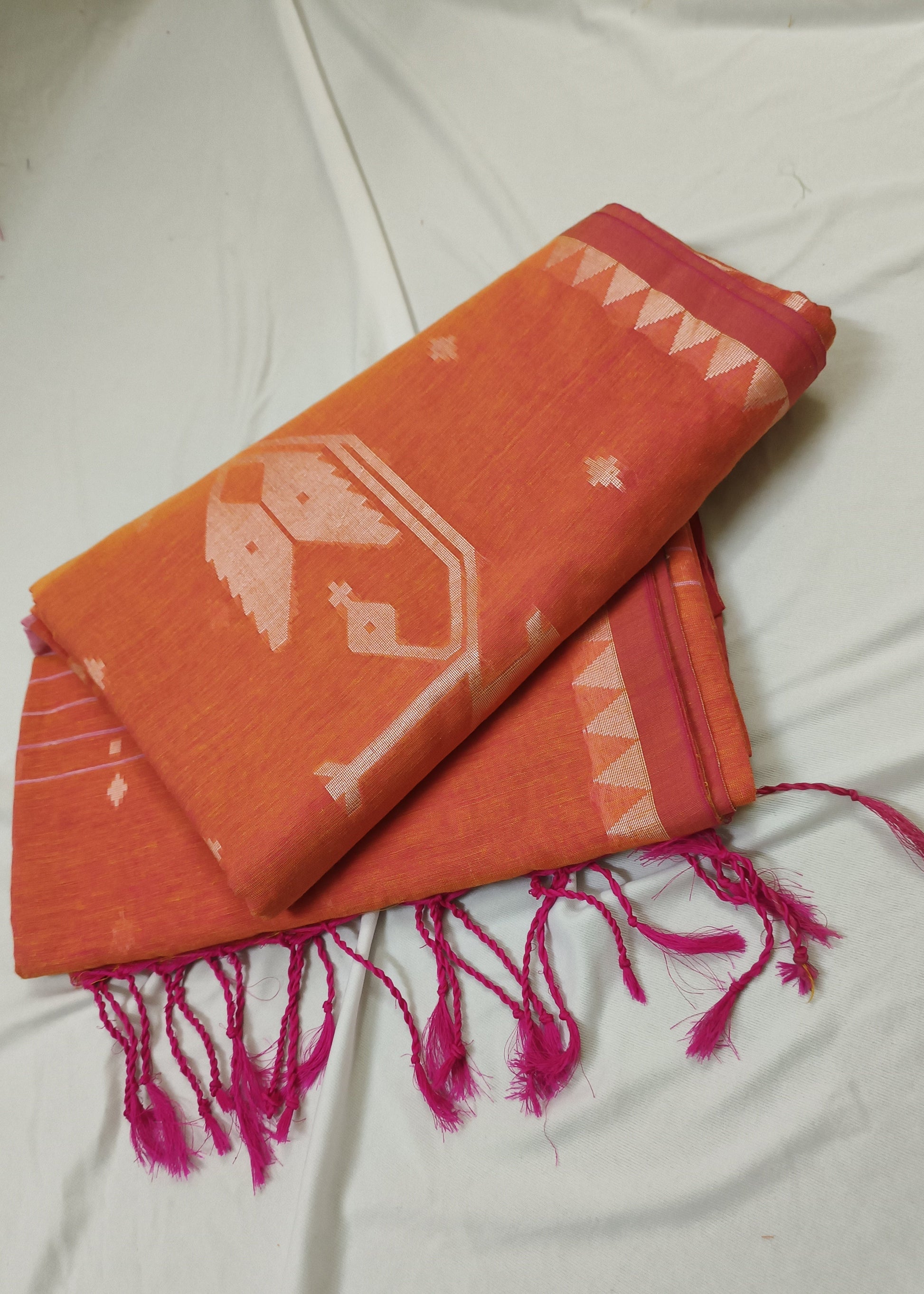 Orange scarf with pink tassels on a white fabric background