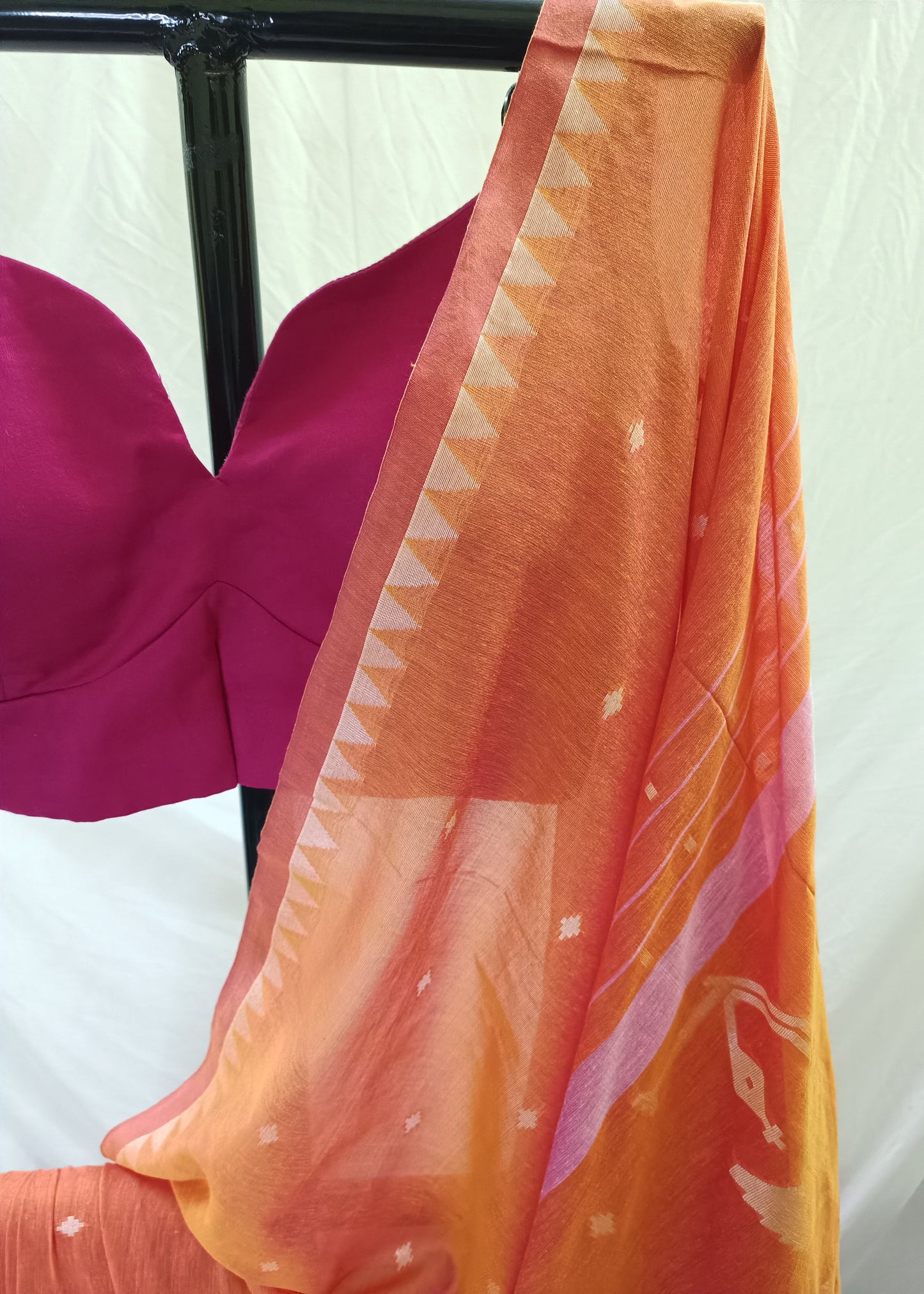 Orange fabric with white patterns draped over a pink garment on a white background