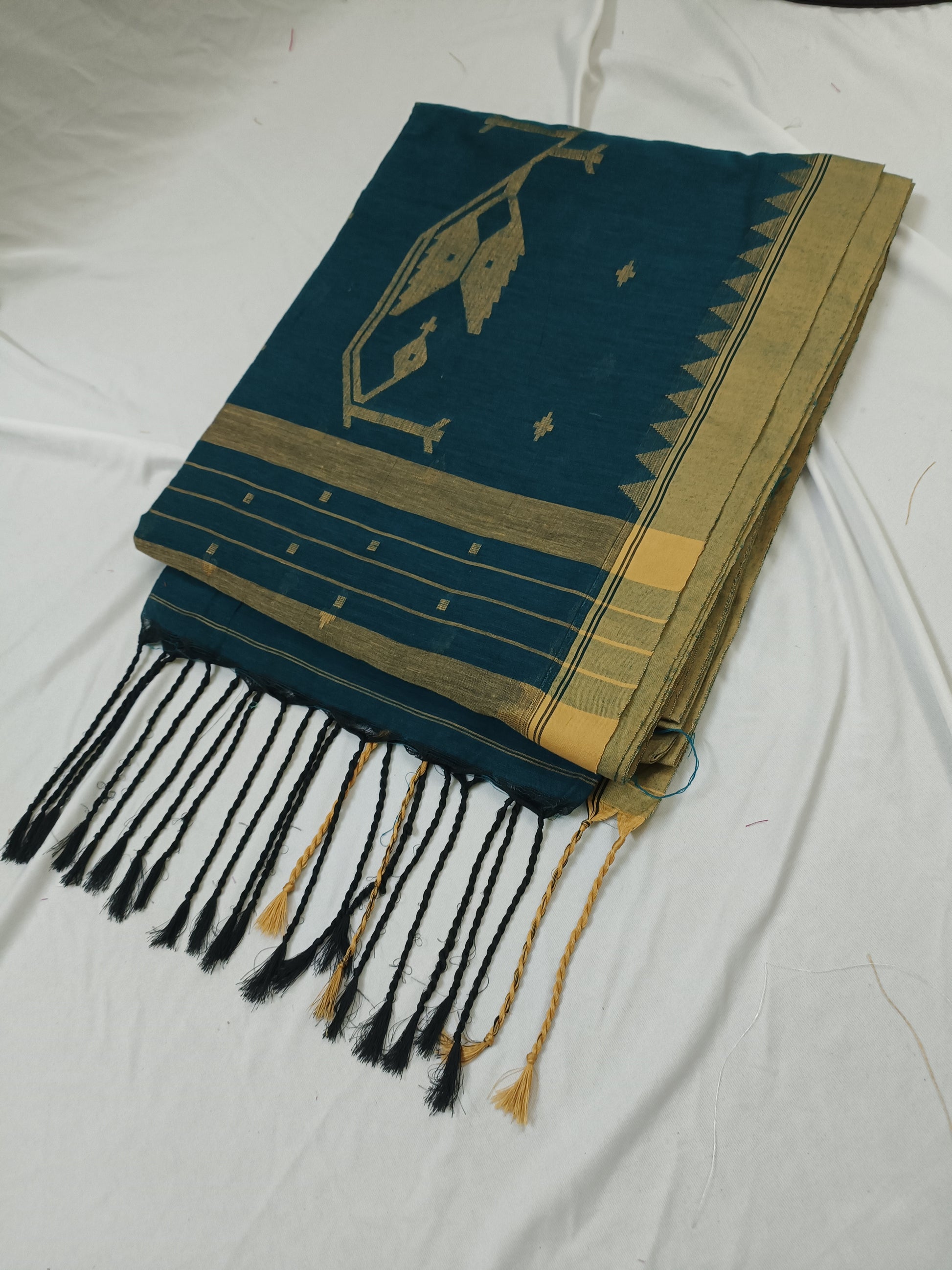 Green and gold patterned scarf with black tassels on a white background