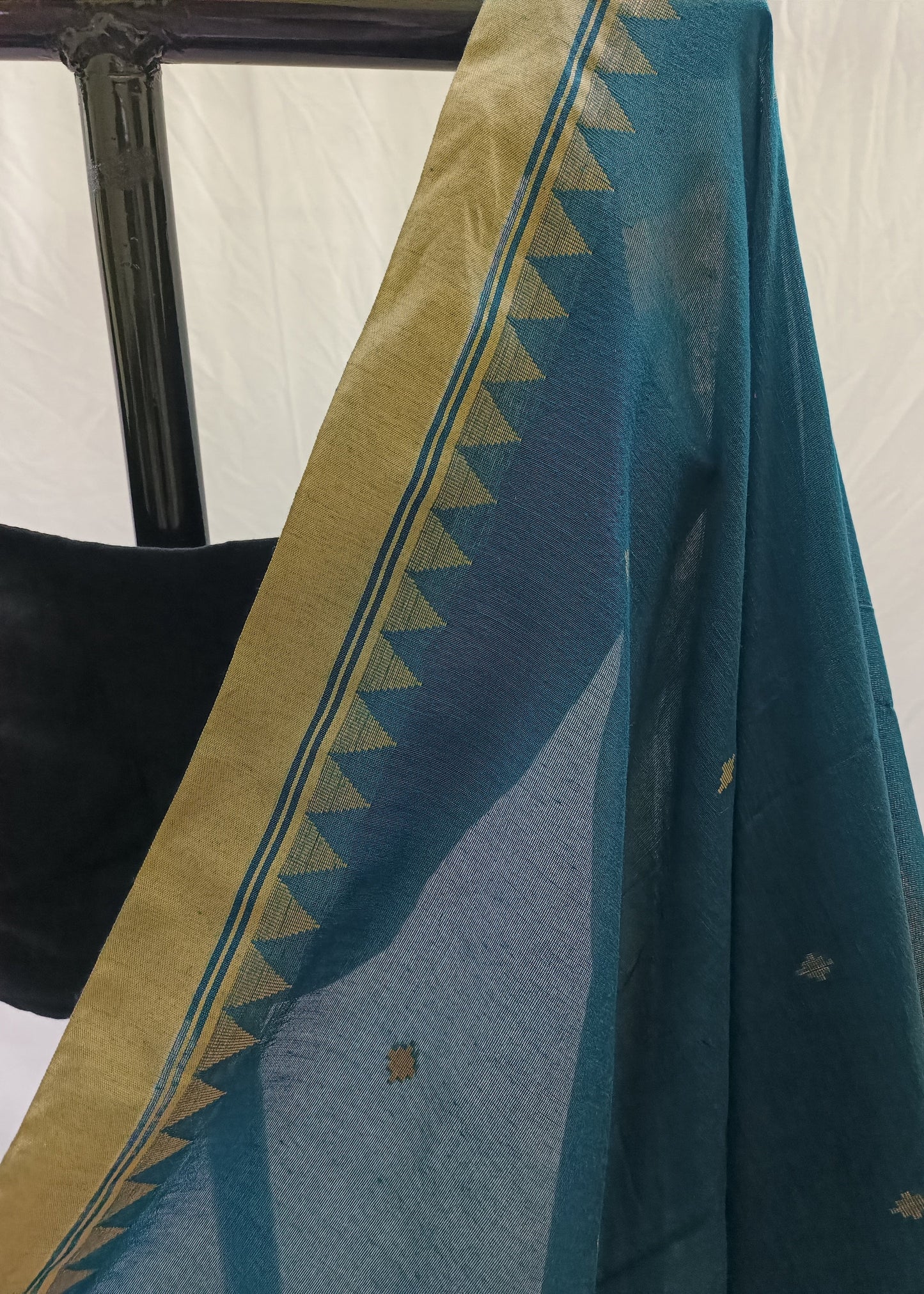 Teal fabric with gold border draped over a chair against a white background