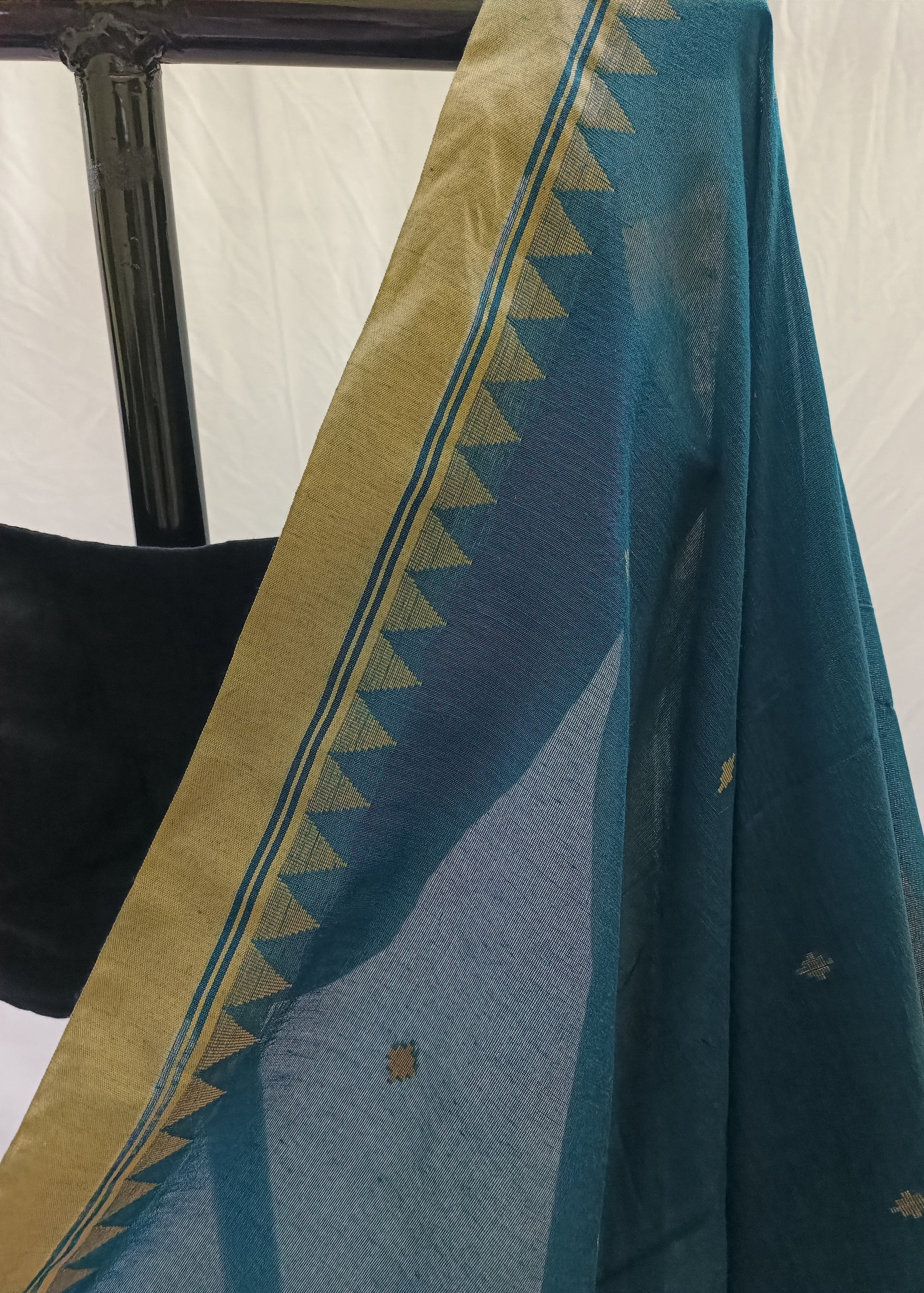 Teal fabric with gold border draped over a chair against a white background