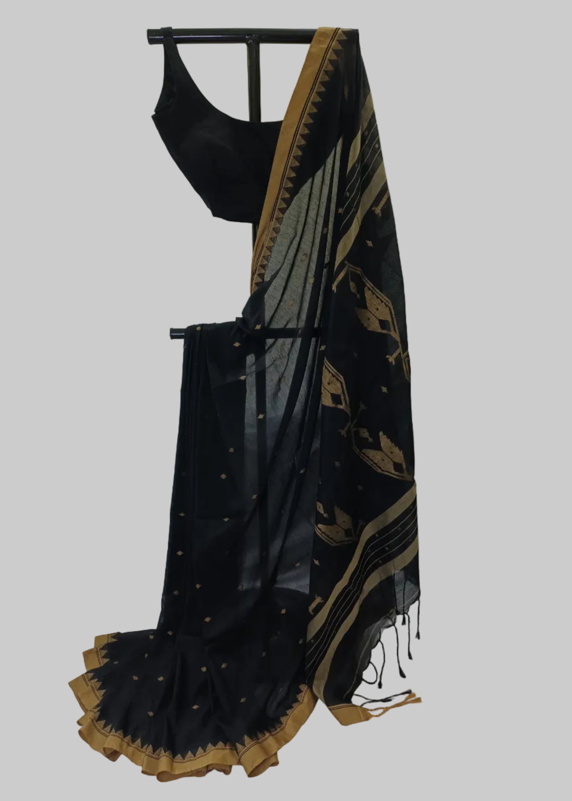 Black saree with gold border draped over a black rod against a white background