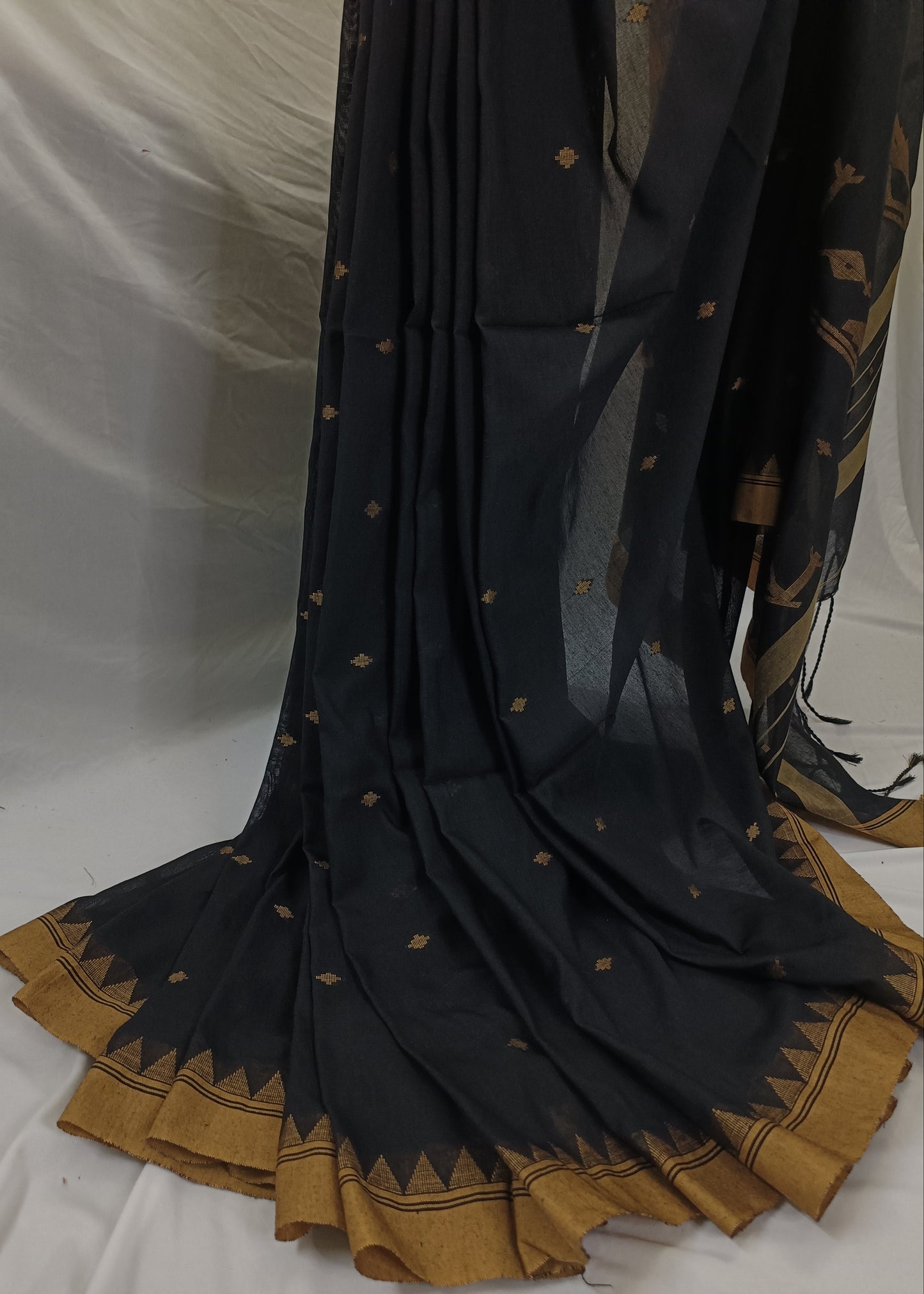 Black saree with gold border and patterns on a white background