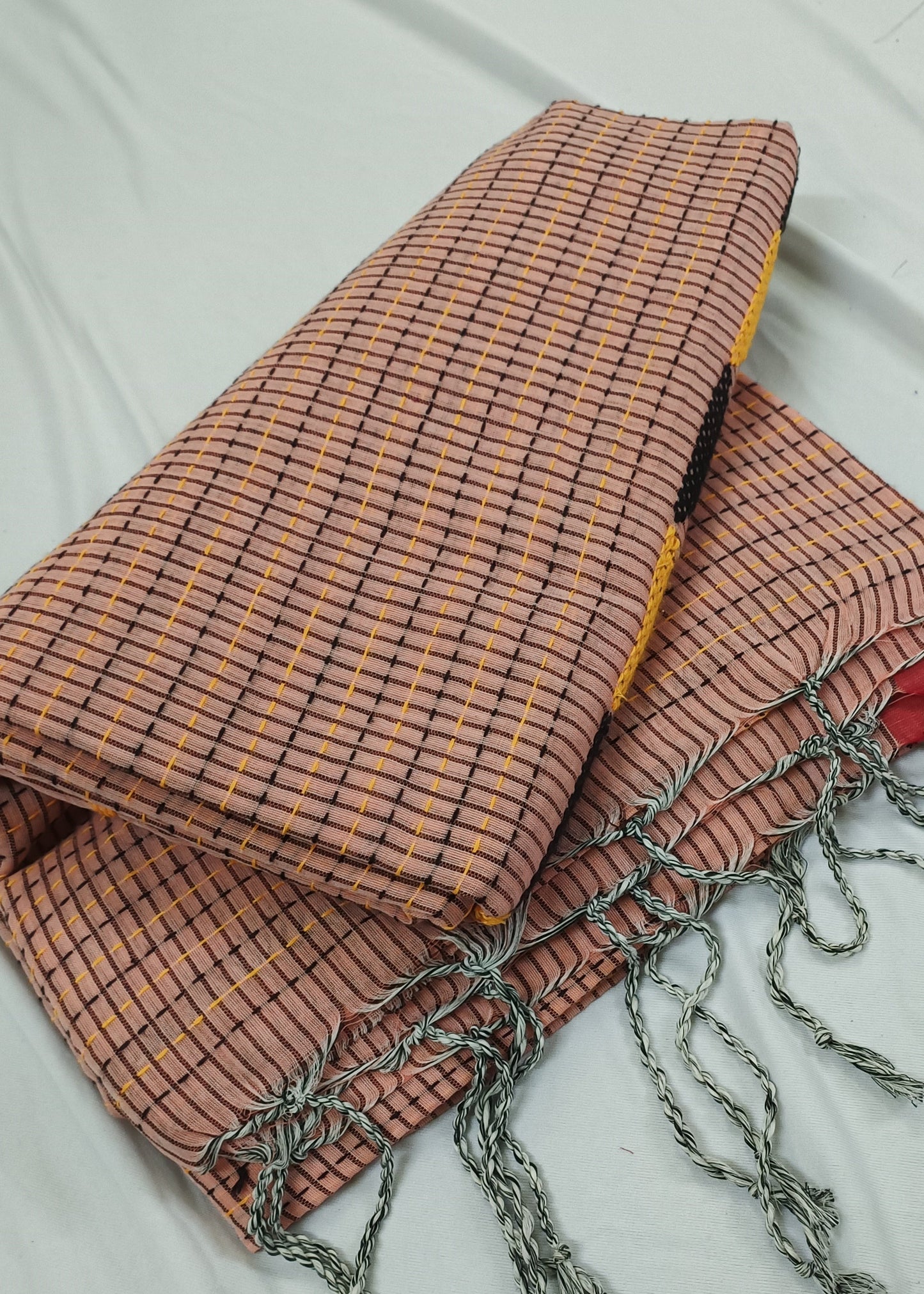 Textile with checkered pattern and tassels on a white background