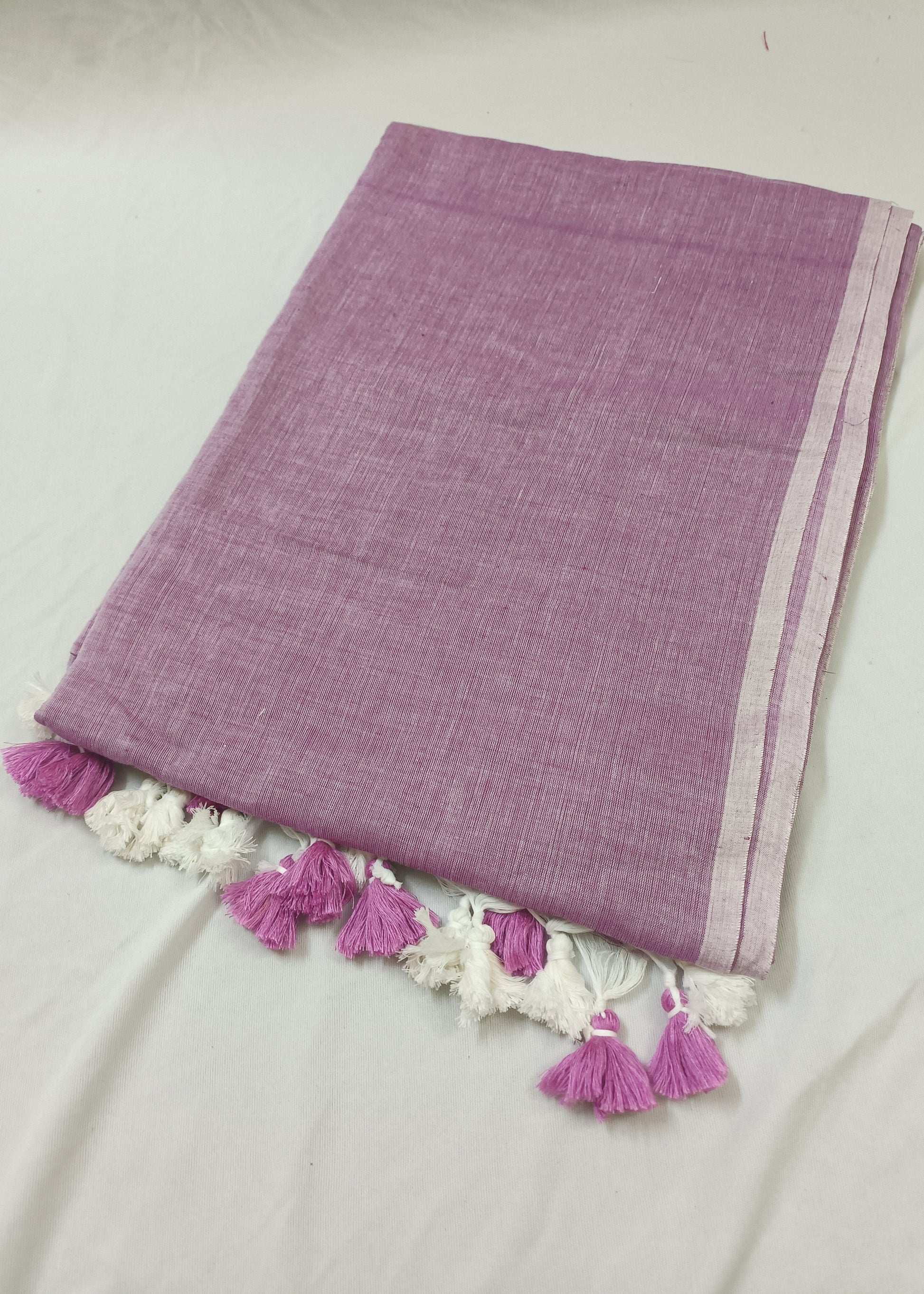 Purple fabric with white lace and pink tassels on a light gray background