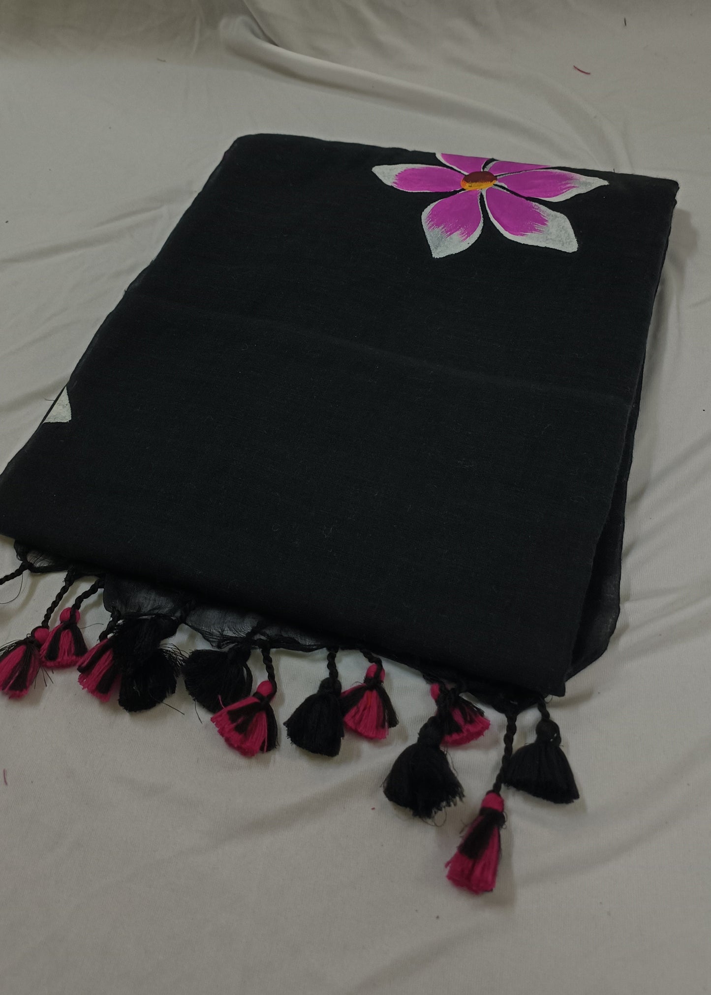 Black saree with pink flower and tassels on a white background