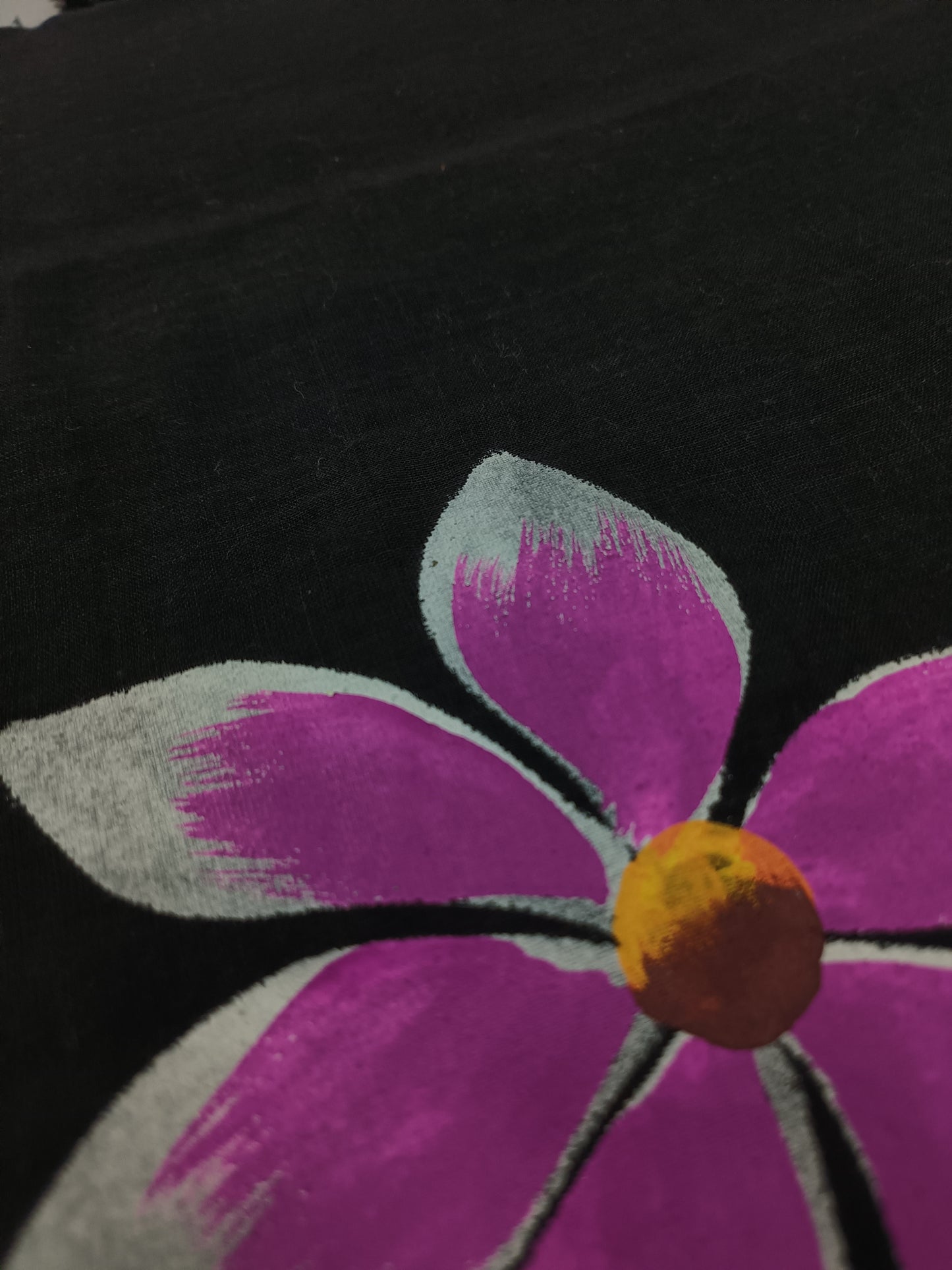 Close-up of a purple flower with a yellow center on a black background