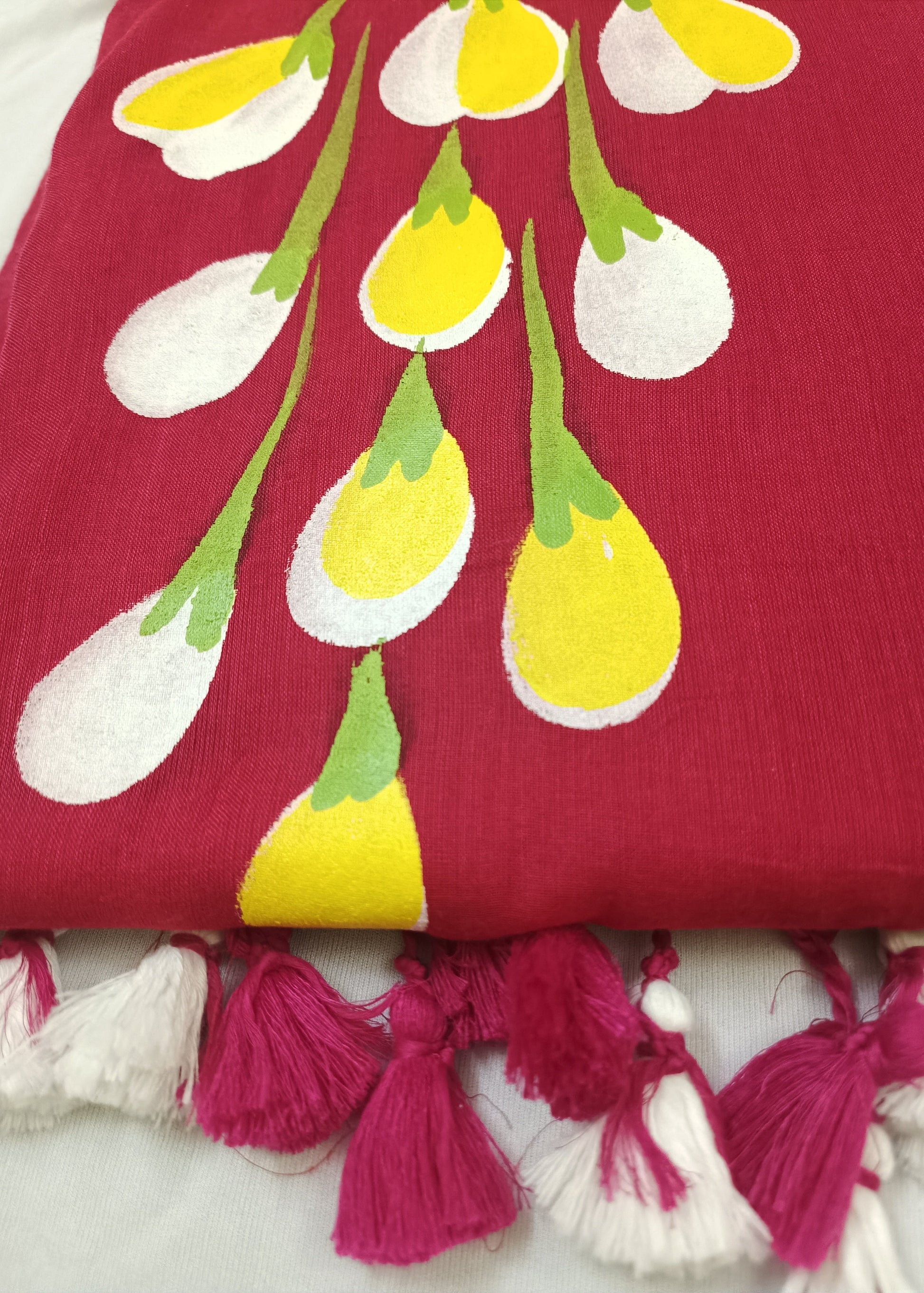 Red fabric with yellow and white floral patterns and pink tassels on a white background