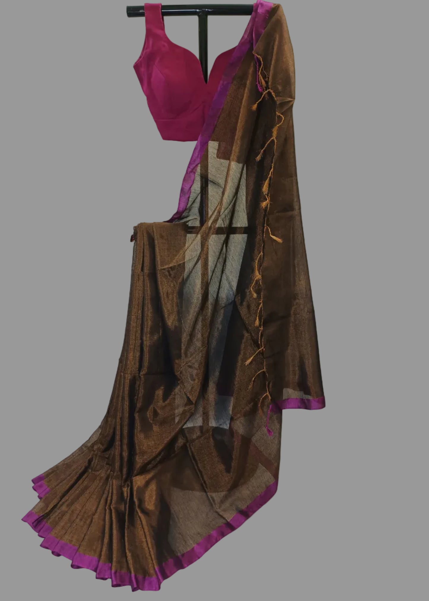 Brown saree with purple border draped over a stand on a white background