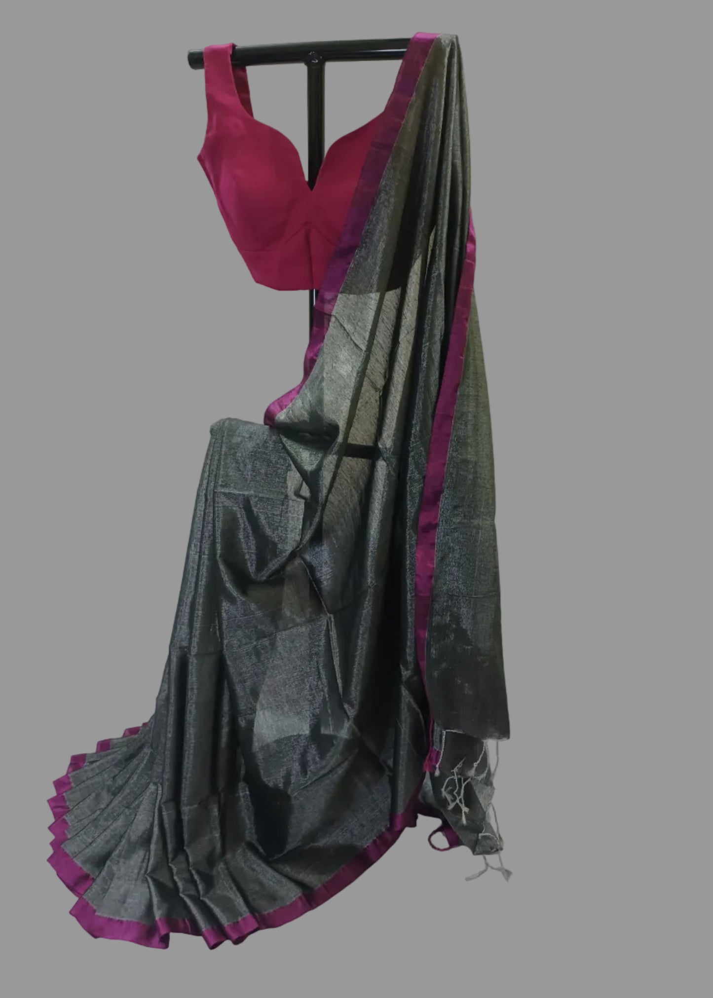Saree with a pink blouse draped over a black rod against a white background