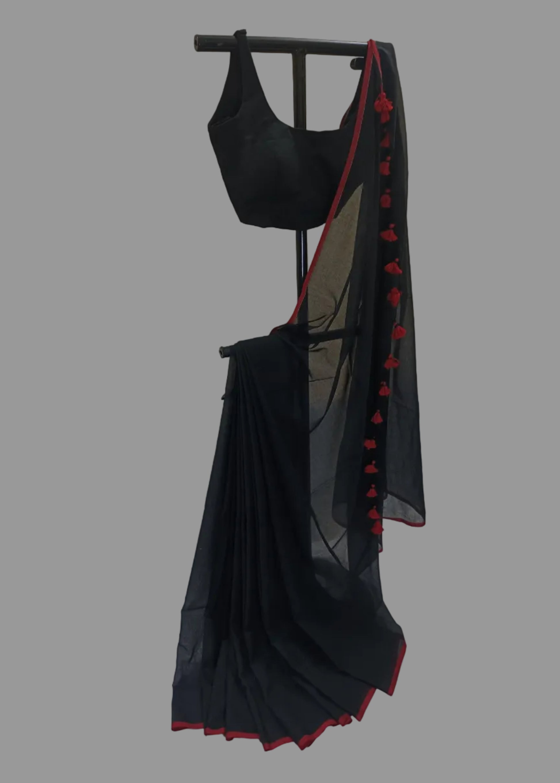 Black saree with red border on a stand against a neutral background