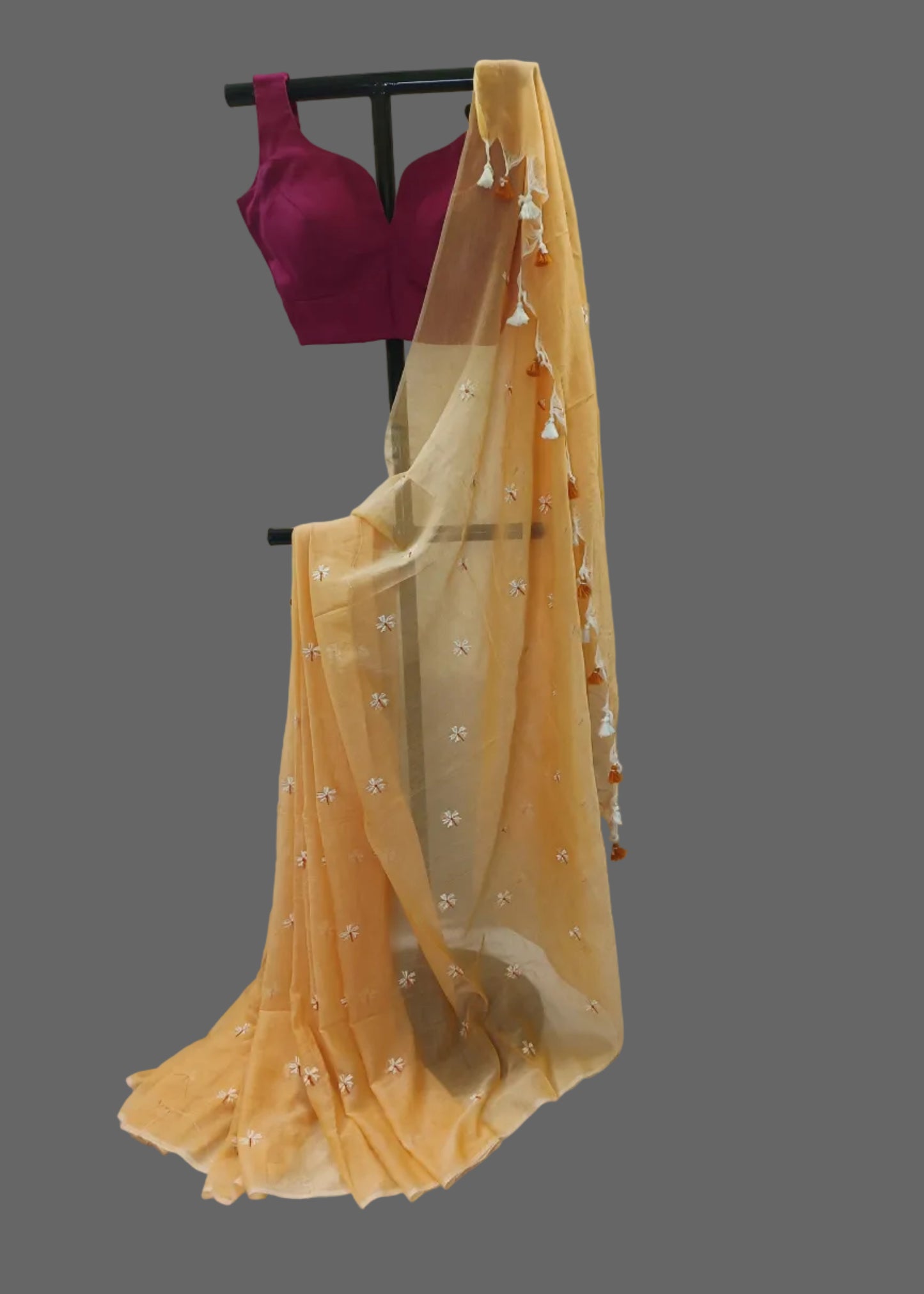 Yellow saree with floral patterns draped over a purple blouse on a mannequin against a white background.