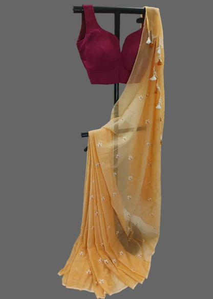 Yellow saree with a red blouse on a black stand against a white background
