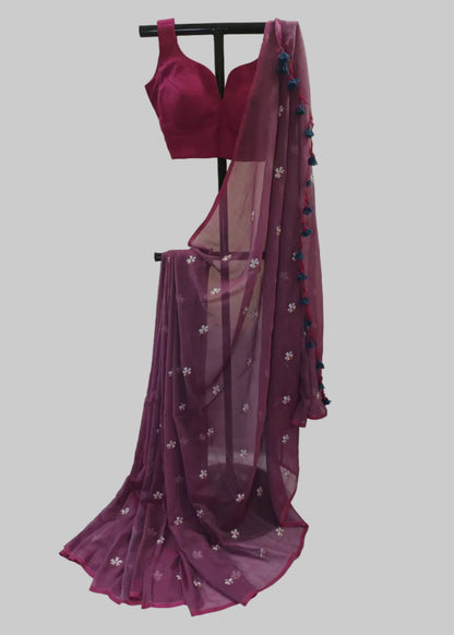 Magenta saree with floral patterns and a matching blouse on a stand against a neutral background