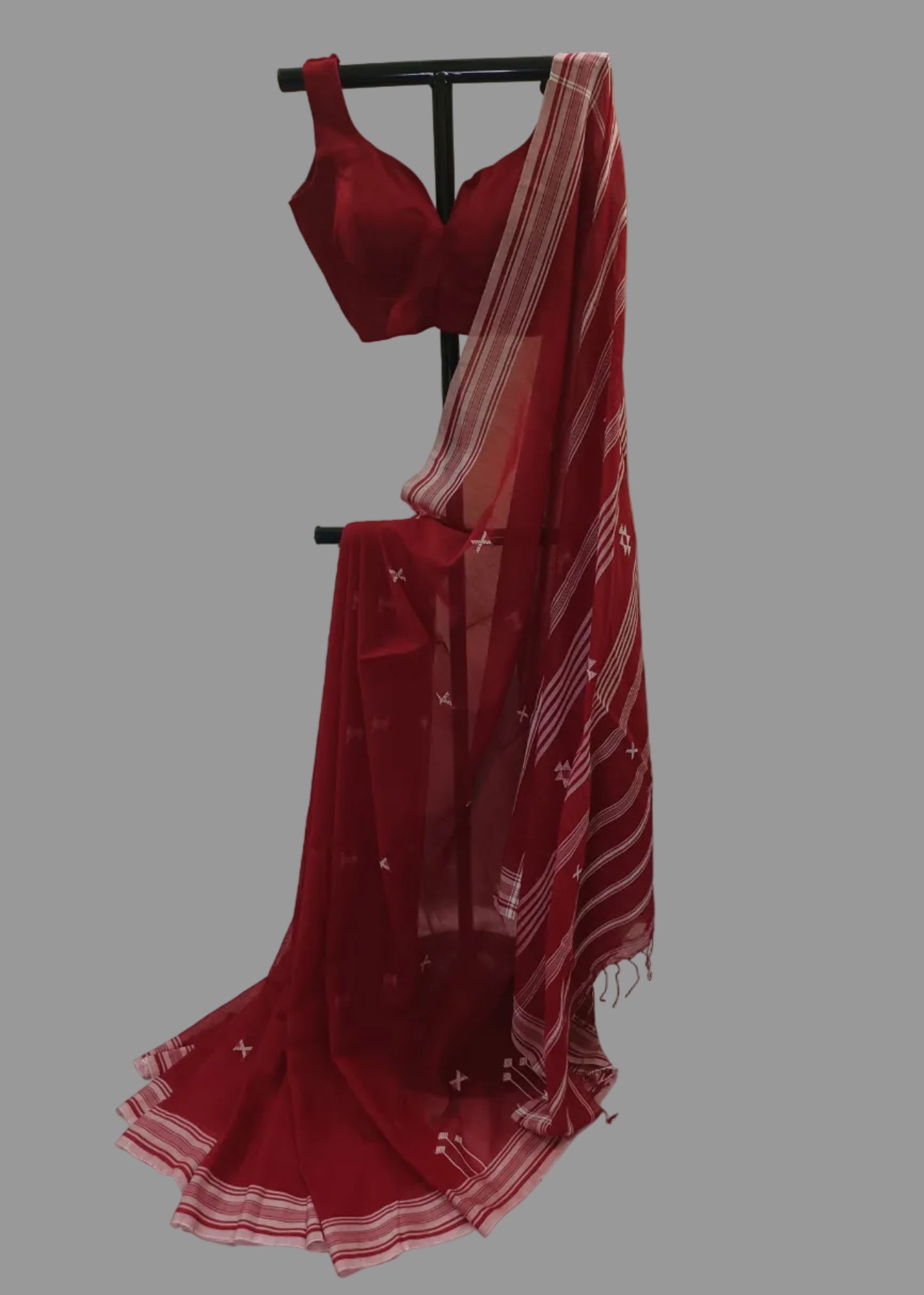 Red saree with a matching blouse on a stand against a white background