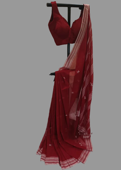 Red saree with a matching blouse on a stand against a white curtain background