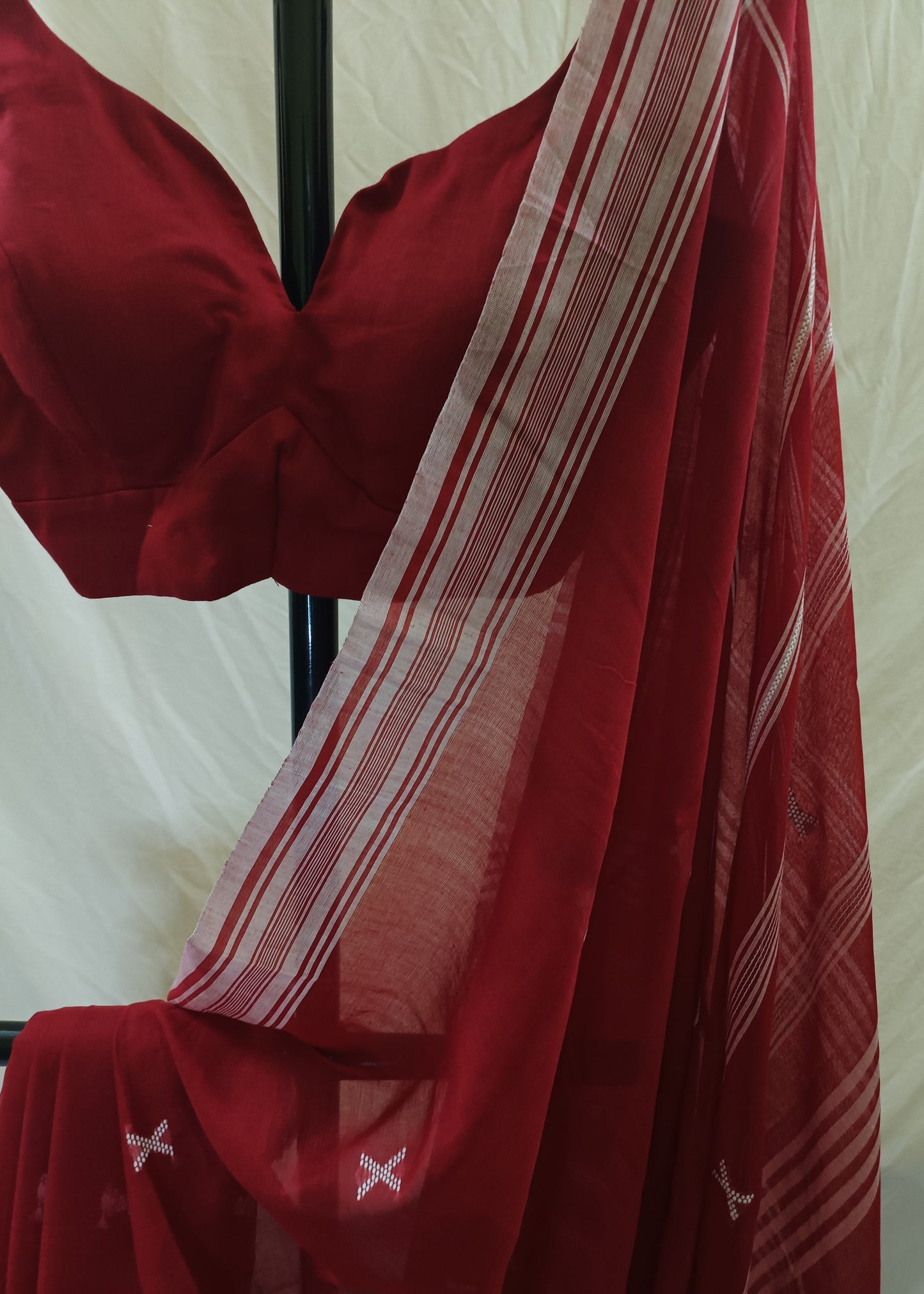 Red saree with white stripes draped over a chair against a white background