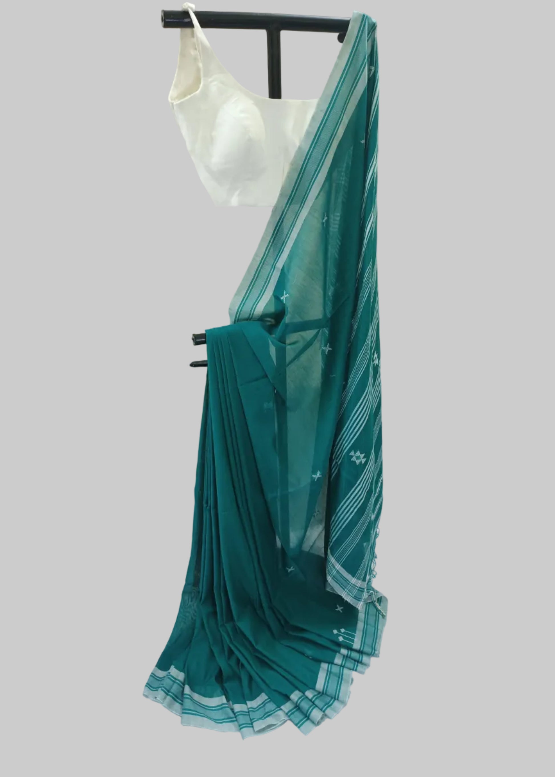 Teal saree with white patterns on a mannequin against a white backdrop