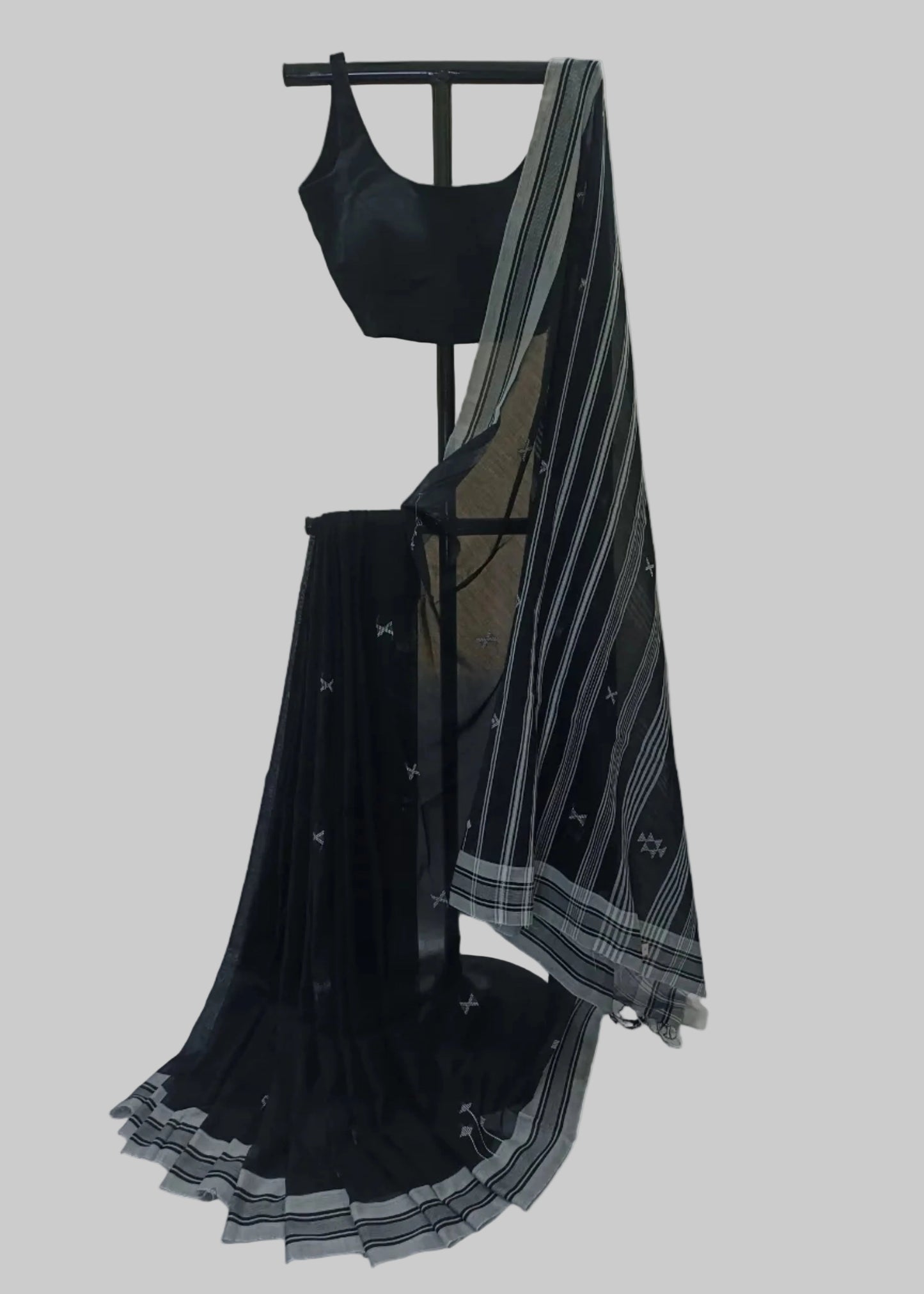 Black saree with white patterns draped over a mannequin against a neutral background