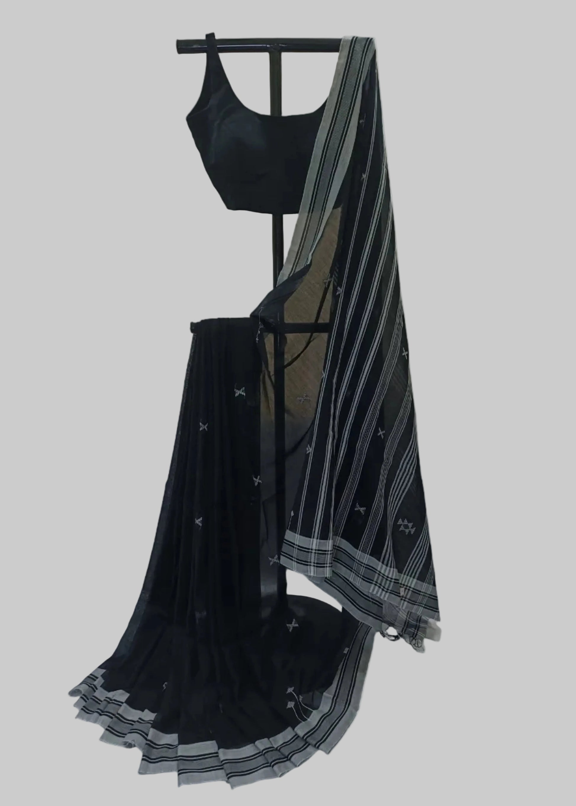 Black saree with white patterns draped over a mannequin against a neutral background