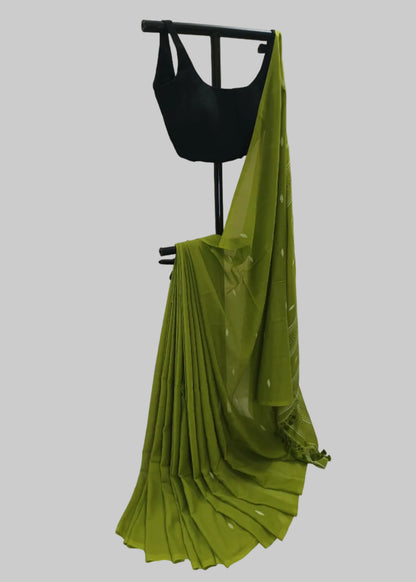 Green saree draped over a black mannequin against a white curtain background