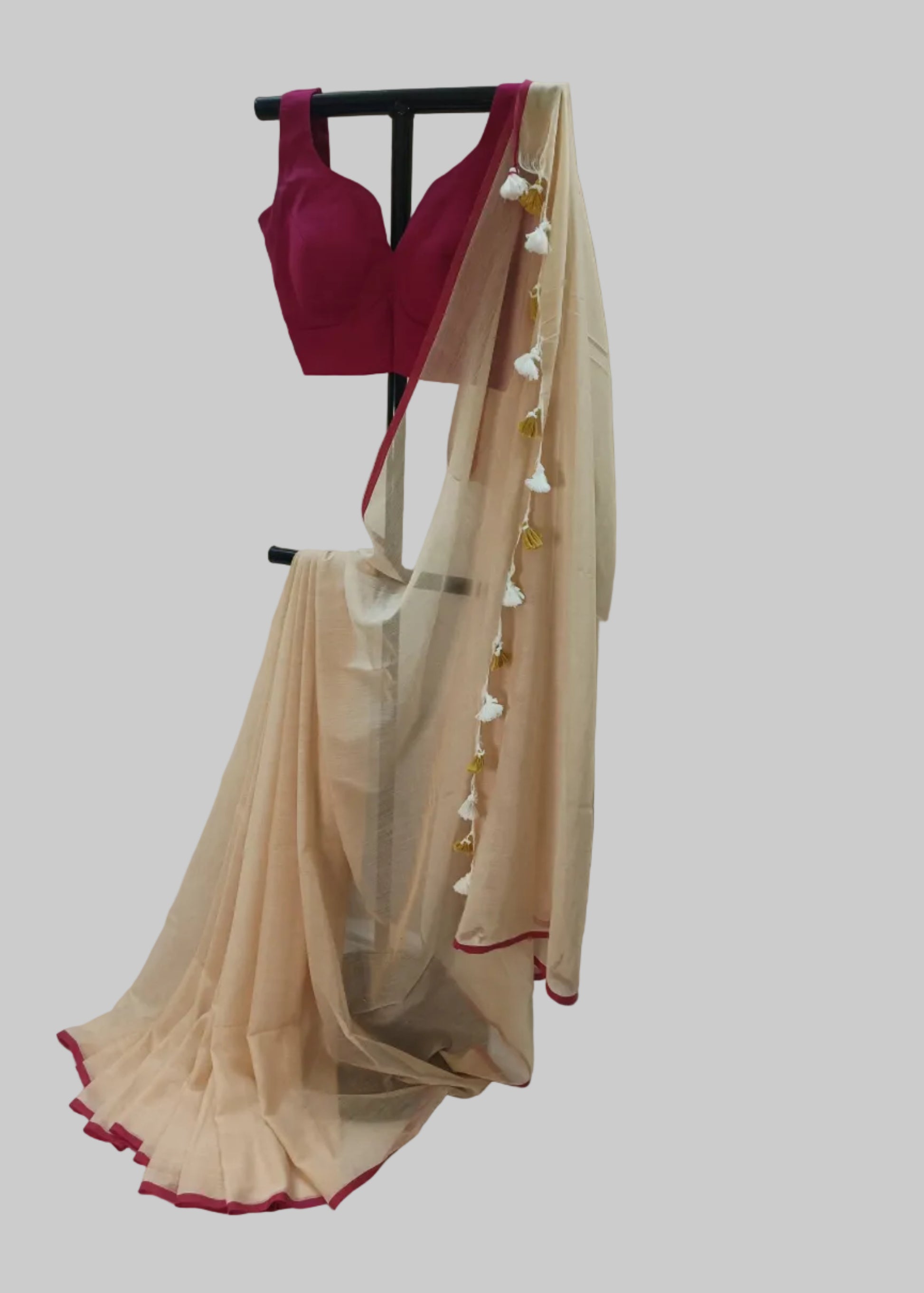 Beige saree with red border and magenta blouse on a mannequin against a plain background