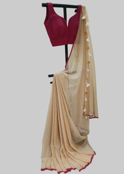 Beige saree with red border and pink blouse on a stand against a plain background