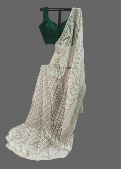 Green blouse with a white lace saree draped over it on a plain background