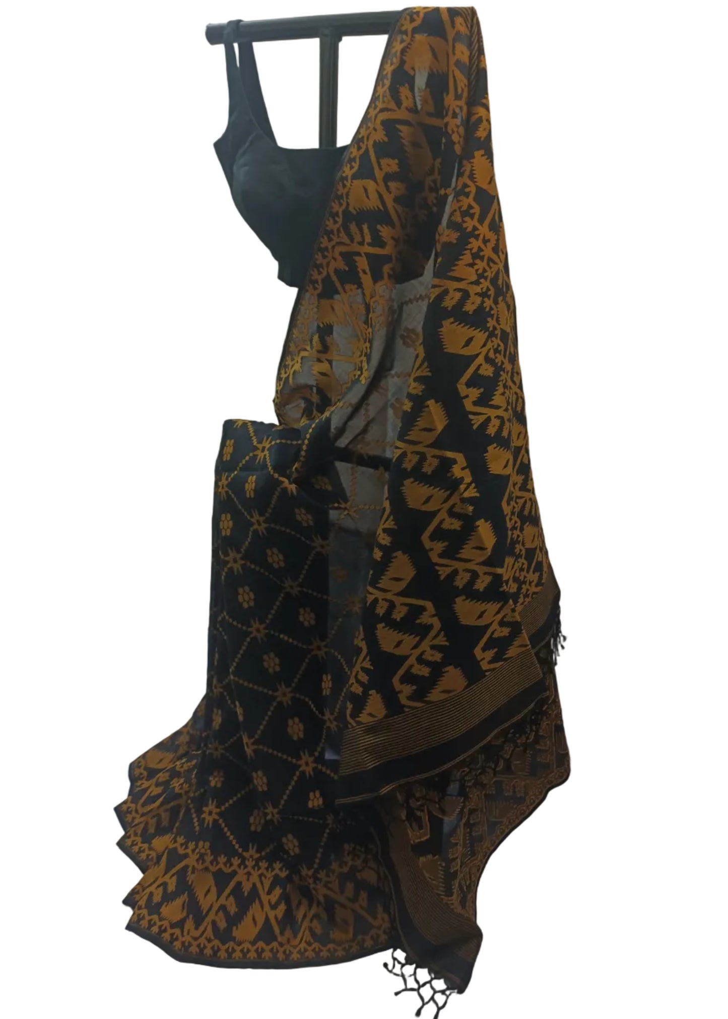 A black saree with a mustard-gold geometric and floral pattern, draped on a black hanger with a matching black blouse visible at the top, set against a draped white fabric backdrop.