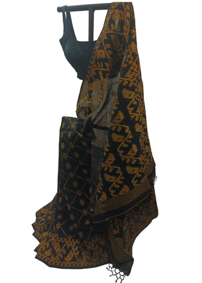 A black saree with a mustard-gold geometric and floral pattern, draped on a black hanger with a matching black blouse visible at the top, set against a draped white fabric backdrop.