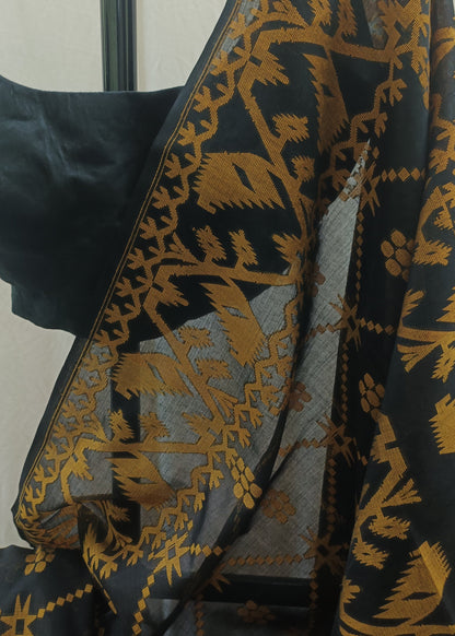 Black saree with a gold floral and geometric pattern, paired with a solid black blouse, shown against a neutral off-white background.