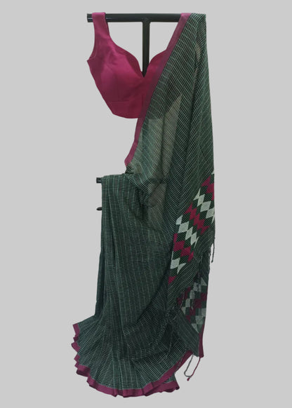 A dark green and white checkered saree with a magenta pink blouse and border, displayed on a black clothing stand against a draped cream fabric backdrop.