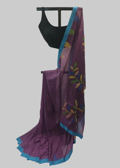 A purple saree with a blue border and multicolor floral print, paired with a black blouse, displayed on a stand against a white fabric backdrop.