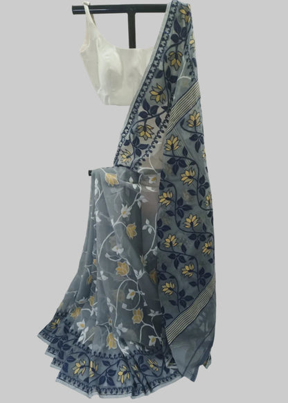 A sheer gray saree with navy blue and yellow floral patterns, draped over a white blouse on a black hanger stand against a white fabric backdrop.