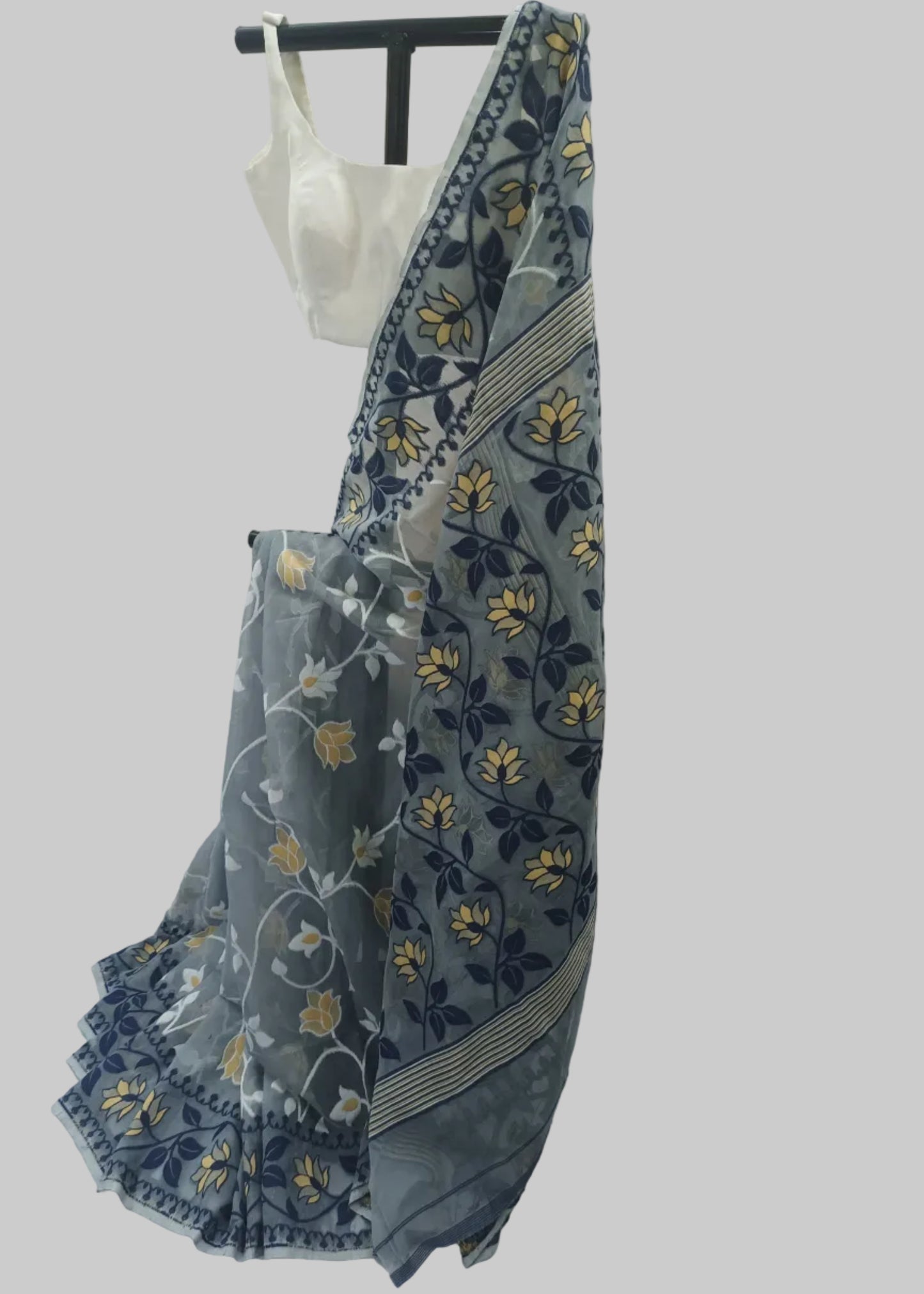 A blue and gray printed saree with yellow floral motifs and a white blouse, displayed on a black hanger against a white fabric backdrop.