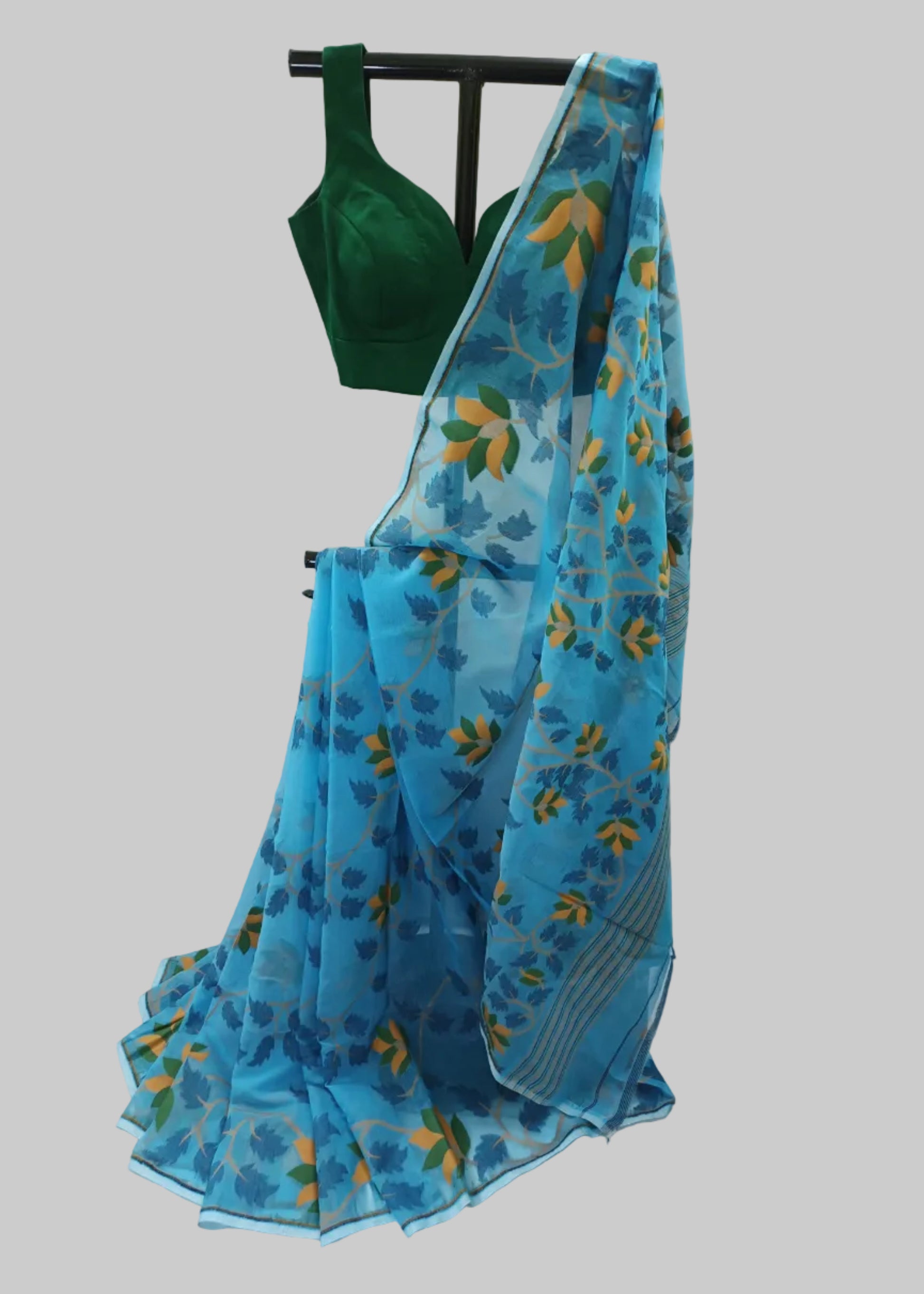 A blue patterned saree draped on a black hanger with a dark green blouse, set against a white fabric backdrop.