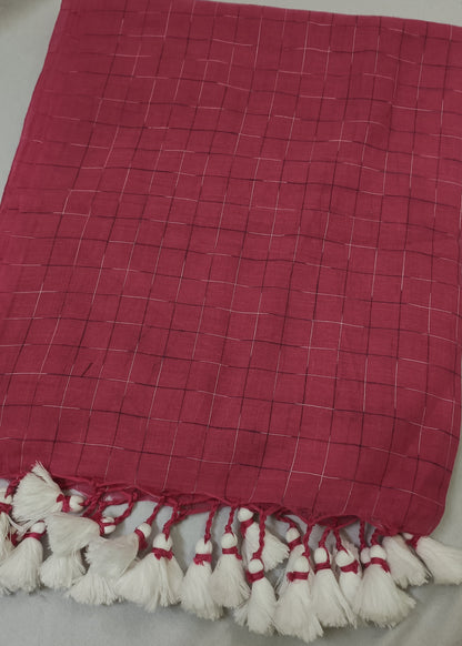 A red checkered sareewith white tassels, laid flat on a light gray fabric background.
