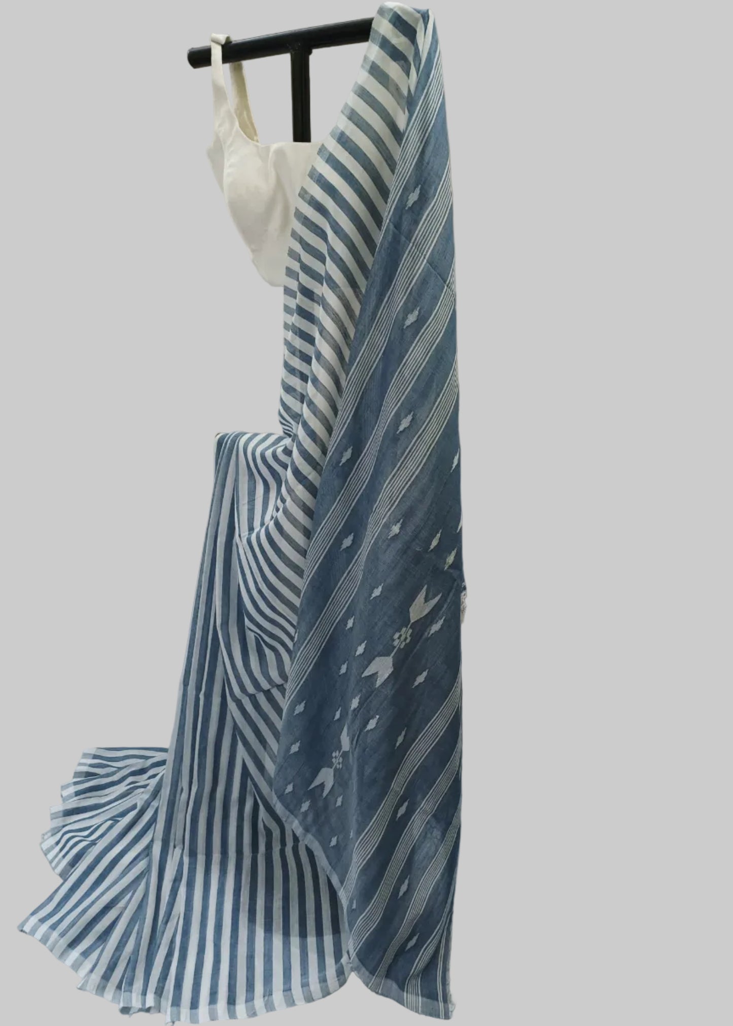 A blue and white striped fabric garment draped over a black hanger against a white fabric backdrop.