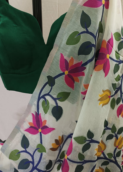 A white organza saree with vibrant floral and vine patterns in pink, yellow, green, and blue, draped over a dark green blouse.